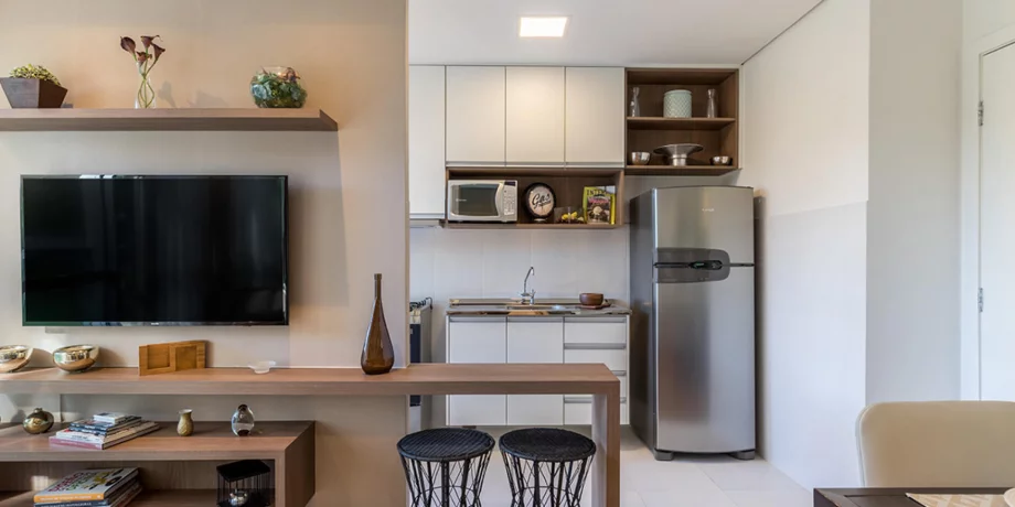 SALA do apto de 50 m² conectada a cozinha americana. A bancada entre a sala e cozinha cria um espaço para refeições e favorece o convívio entre os ambientes.
