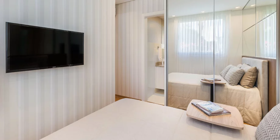 SUÍTE de casal do apto de 50 m², o armário com portas de correr espelhadas é uma sugestão de decoração que aproveita o espaço.