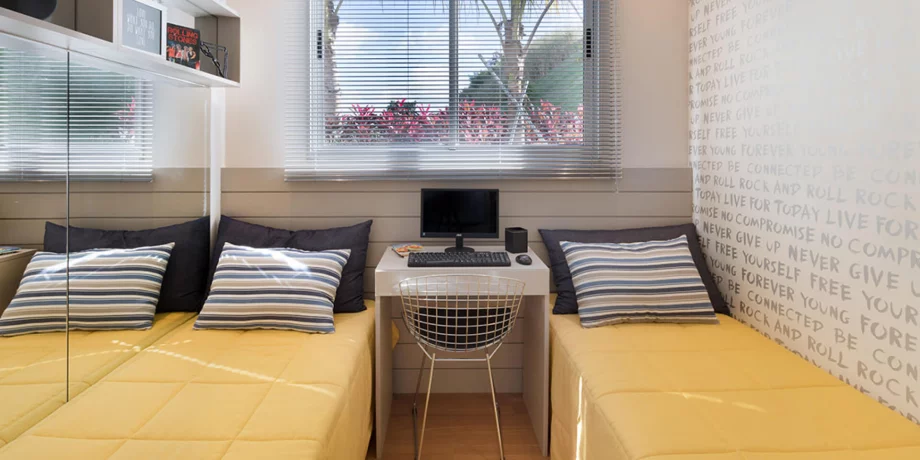 QUARTO do apto de 50 m² com espaço para duas camas de solteiros e mesa para computador. O apartamento é ideal para receber confortavelmente famílias com até dois filhos.